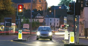 Car waiting at traffic lights at dusk in a town.