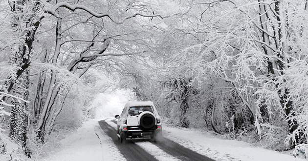 4 x 4 vehicle drives along rurlal road after heavy snow.