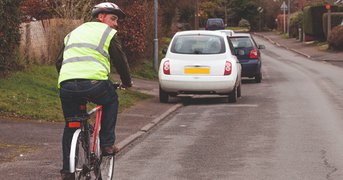 Cyclist with helmet and high visiblity waistcoat checks over their shoulder for safety.