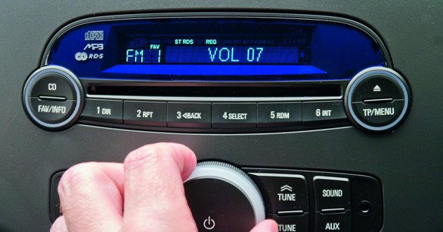 In-car entertainment controls, volume being adjusted by hand.