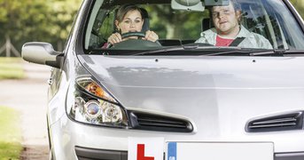 Learner driving with instructor, day.