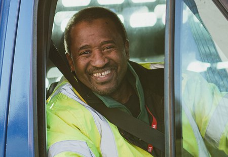 Large goods vehicle driver smiles through open window of cab.