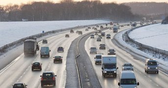 Motorway surrounded by snowy conditions.