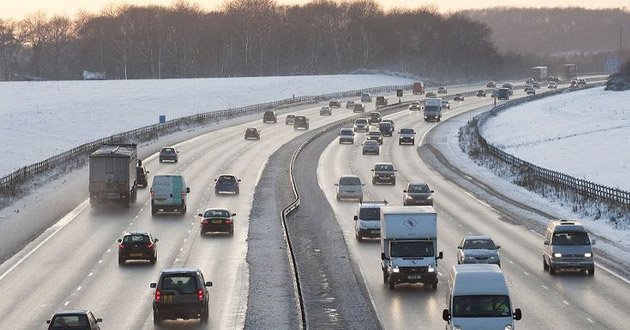 Motorway surrounded by snowy conditions.